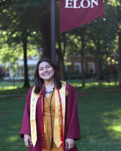 Young woman in a maroon graduation gown with a yellow stole and red cord