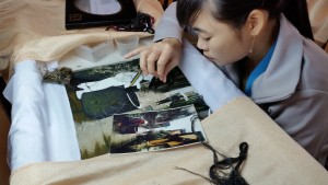 A low paid silk factory employee hand sewing a picture that takes a month to complete